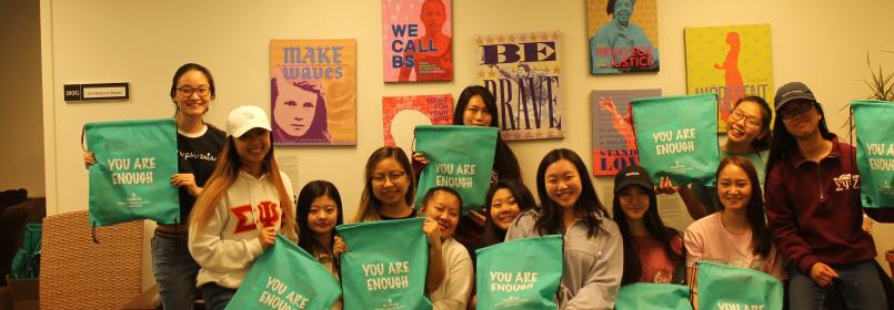 Group of 12 women holding green 'You Are Enough' bags.