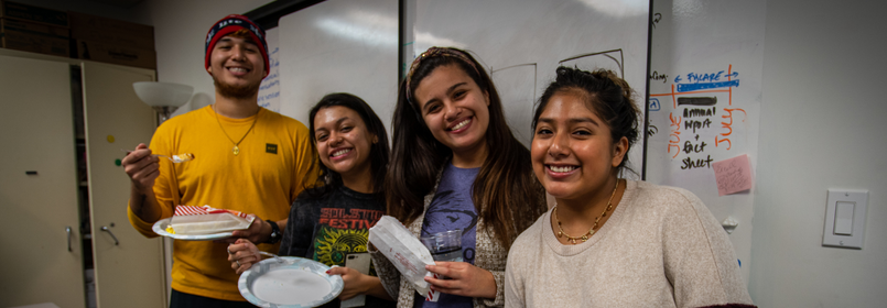Four program attendees smiling with plates of food and drinks