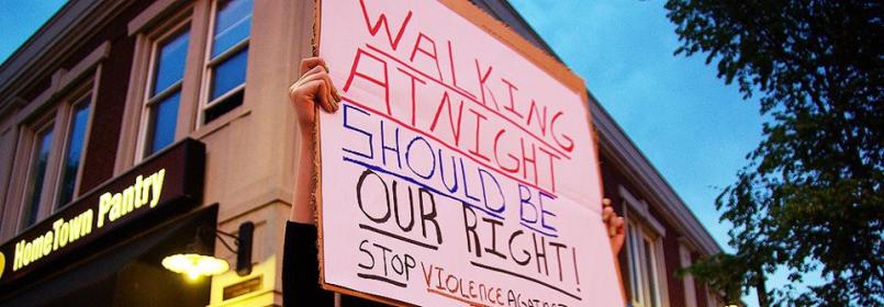 Person holding poster with text reading "Walking at Night should be our right! Stop Violence Against .." on Green Street